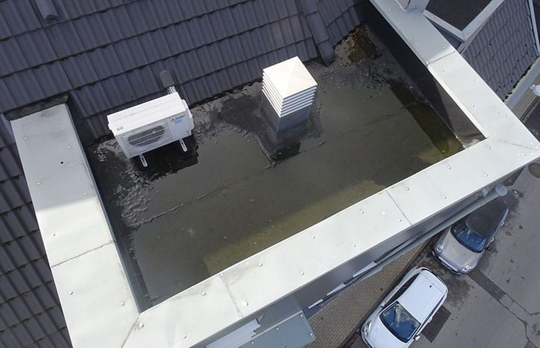 Wasser steht auf dem Flachdach eines Mehrfamilienhauses